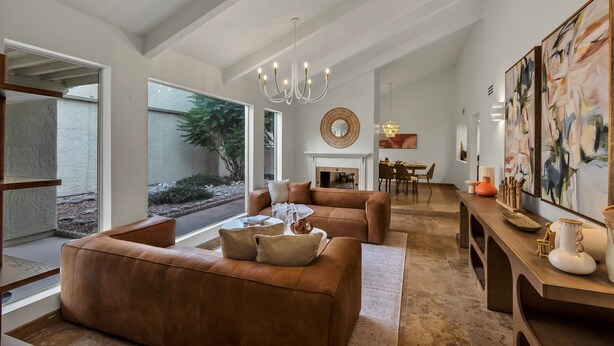 A spacious living room with a fireplace, large windows, and a dining area. - Del Rio Luxe | Design-Driven 3BR Home with Pools & Tennis (Tucson)