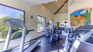 Ein modernes Fitnessstudio mit Cardiogeräten, Krafttrainingsgeräten und großen Fenstern mit Blick ins Freie.