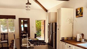 A kitchen with a central island, wooden chairs, a stove, a refrigerator, and a dining table.
