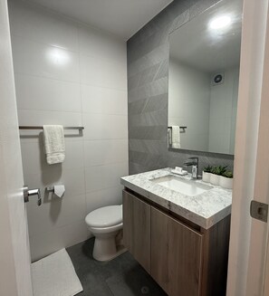 Een moderne badkamer met toilet, wastafel en spiegel.