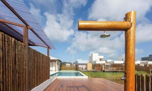 Une terrasse en bois avec une piscine, une clôture en bois et un bâtiment moderne en arrière-plan.