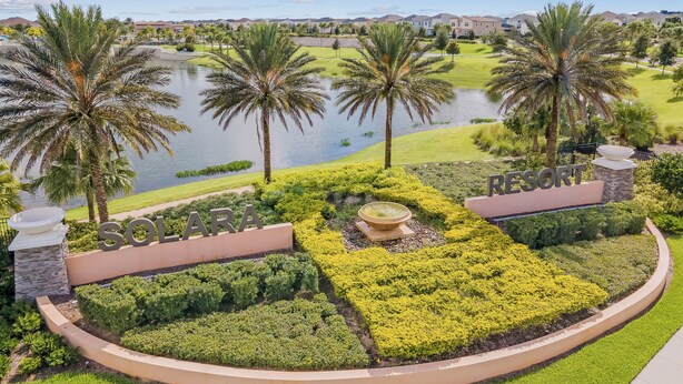 Un resort con un jardín cuidado, un lago y cielo despejado.