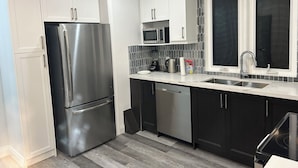 Une cuisine moderne dotée d’appareils électroménagers en acier inoxydable, de meubles de couleur sombre et d’un dosseret carrelé.