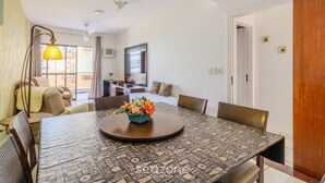 Ein Hotelzimmer mit Esstisch, Stühlen, einer Couch, einem Fernseher und Deckenventilator.