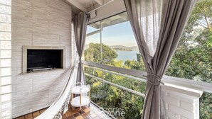 A balcony with a TV, a hammock, and a view of a lake. - Bela Vista Duplex W/bbq in Bombinhas Ags0642 (Bombinhas)
