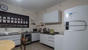 Una cocina compacta con armarios blancos, microondas, estufa y refrigerador.