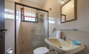 A bathroom with a glass-enclosed shower, a white toilet, a sink with a blue bowl, and a mirror on the wall. - House 100m From the Beach in Barra Velha Aia2200 (Barra Velha)