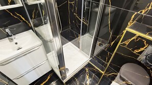 Un bagno con box doccia in vetro, lavandino bianco e servizi igienici.