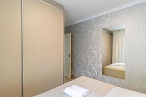 Una habitación de hotel con una cama, un armario, un espejo y una puerta.
