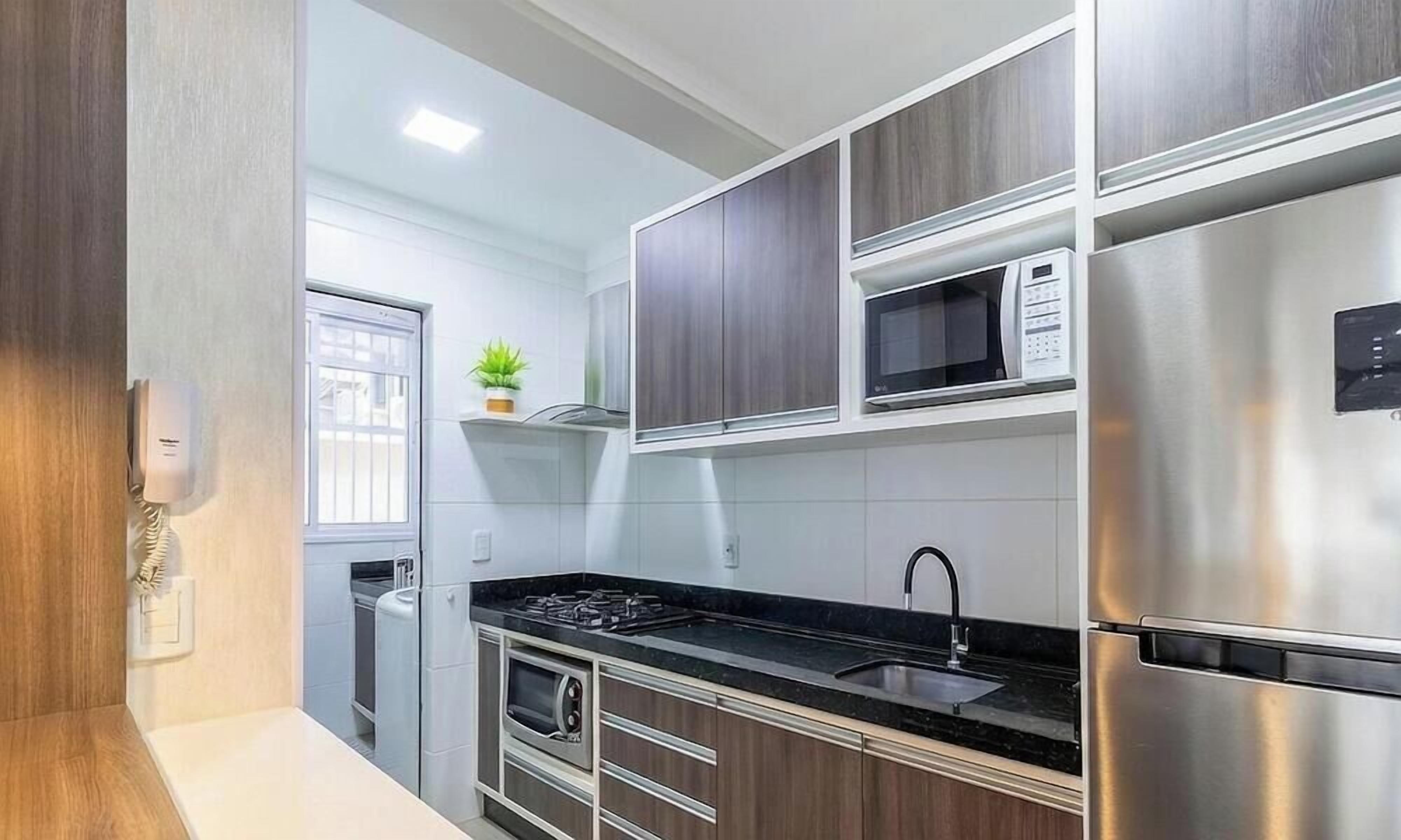 A modern kitchen with stainless steel appliances, wooden cabinets, and a black countertop.