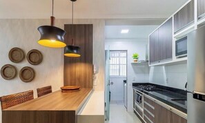 Una cocina moderna con armarios de madera, una estufa de acero inoxidable y un comedor con mesa y sillas de madera.