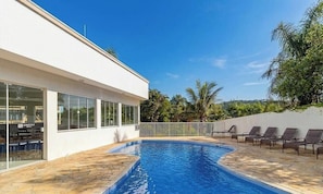 Ein modernes GebĂ€ude mit Pool, AuĂenbereich und Blick auf Palmen.