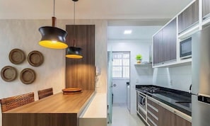 A modern kitchen with wooden cabinets, a stainless steel stove, and a dining area with a wooden table and chairs.