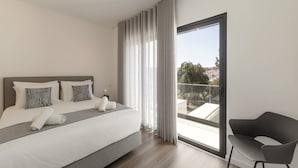 Ett modernt hotellrum med en stor säng, en balkong med utsikt och en modern stol.