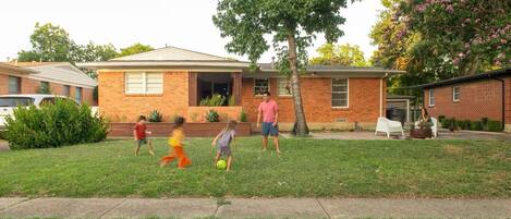 A residential house with a brick exterior, a front yard, and a driveway.