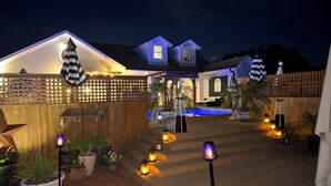 A residential backyard with a swimming pool, potted plants, and outdoor lighting. - Designer 5 Bedroom, 3.5 bath home. Pool, Hot Tub, Pizza Oven, BBQ, bicycles. (Ocean Beach)