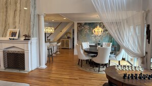 A spacious dining area with a chessboard, a fireplace, and a staircase leading to another level. - Designer 5 Bedroom, 3.5 bath home. Pool, Hot Tub, Pizza Oven, BBQ, bicycles. (Ocean Beach)