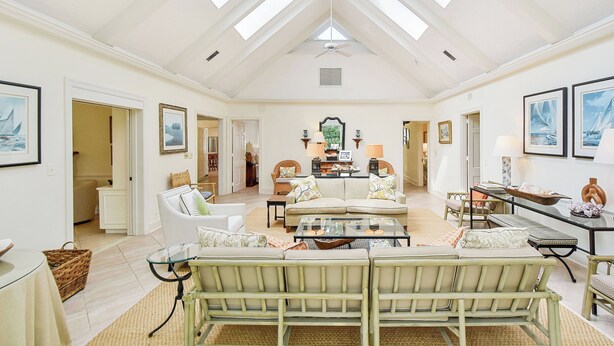 A spacious living room with high ceilings, skylights, and a central seating area with a sofa and chairs. - Charming Sea Island Cottage • Steps to Beach • Sleeps 10 (Sea Island)