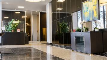 A modern lobby with a reception desk, a fireplace, and a large abstract painting.