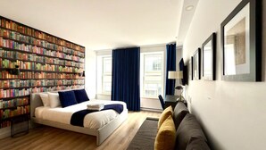A modern hotel room with a large bookshelf, a sofa, a bed, and a desk. - Elegant Loft in Downtown Québec City (Québec City)