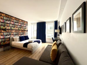 A modern hotel room with a large bookshelf, a sofa, a bed, and a desk. - Elegant Loft in Downtown Québec City (Québec City)