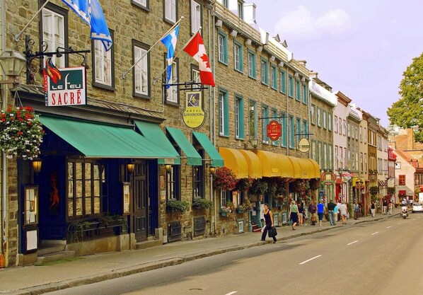 A street with buildings, flags, and outdoor seating areas.