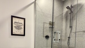 A modern bathroom with a glass-enclosed shower, a toilet, and a framed historical document on the wall. - Elegant Loft in Downtown Québec City (Québec City)