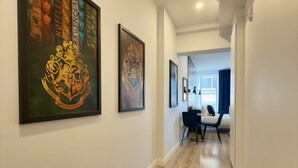 A hallway with framed artwork on the walls, a patterned rug on the floor, and a dining area in the distance. - Elegant Loft in Downtown Québec City (Québec City)