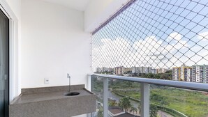 A balcony with a granite countertop and sink, overlooking a residential area with buildings and greenery. - 3 Quartos no Evian Thermas Residence - Etha604 (Caldas Novas)