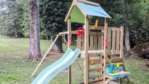 A wooden playhouse with a slide, a climbing net, and a small table with toys. - Cozy home in Petrinja with house a panoramic view (Petrinja)
