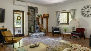 A cozy living room with a stone fireplace, a large clock, and a comfortable seating area. - Cozy home in Petrinja with house a panoramic view (Petrinja)