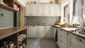 A kitchen with white cabinets, a sink, and a window with curtains. - Cozy home in Petrinja with house a panoramic view (Petrinja)