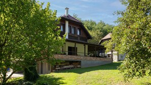 A traditional wooden house with a sloped roof, a brick foundation, and a covered porch. - Cozy home in Petrinja with house a panoramic view (Petrinja)
