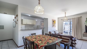Un comedor con una mesa cubierta por un mantel floral, sillas de madera y una lámpara de araña.