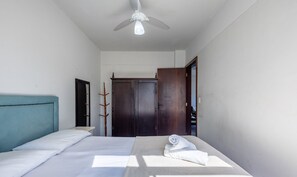 Une chambre à coucher avec un lit, un ventilateur de plafond, une armoire en bois et un miroir.