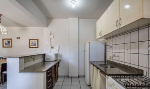 A kitchen with white cabinets, a gas stove, a refrigerator, and a microwave.