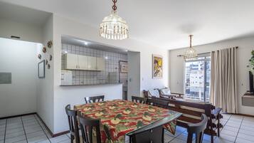 Un comedor con una mesa cubierta por un mantel floral, sillas de madera y una lámpara de araña.