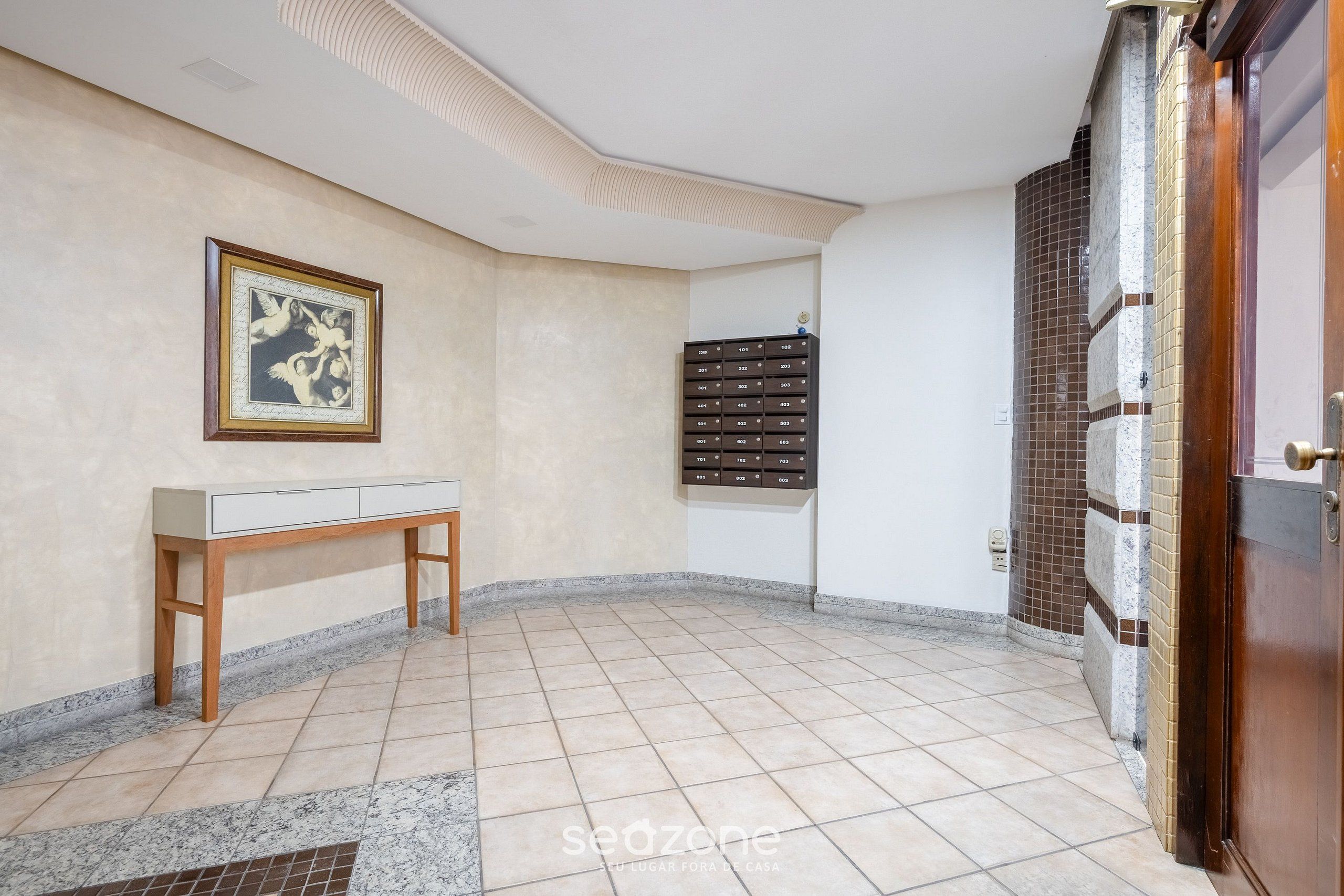 Una habitación con suelo de baldosas, un banco de madera, un cuadro en la pared y un mueble con cajones.