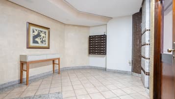 Una habitación con suelo de baldosas, un banco de madera, un cuadro en la pared y un mueble con cajones.