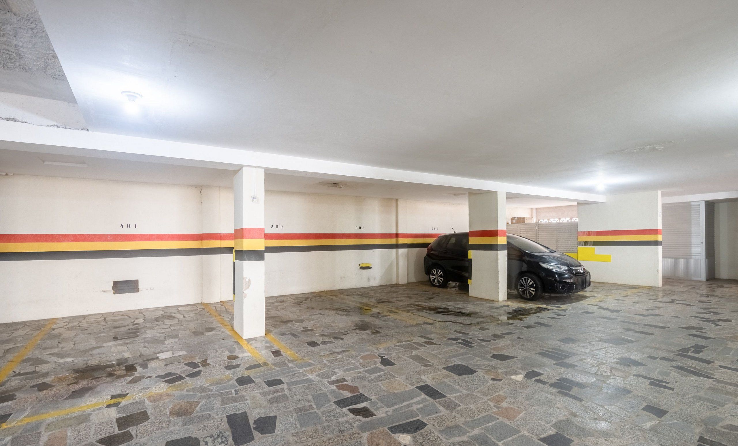 Un estacionamiento con espacios numerados y un coche negro estacionado en uno de ellos.