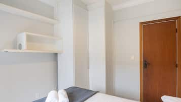 A hotel room with a bed, a wooden door, and a white wardrobe.