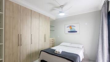 Un dormitorio con cama, armario, ventilador de techo y un cuadro en la pared.