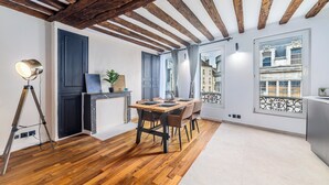 A dining area with a wooden table and chairs, a tripod lamp, and a view of the city through large windows. - Triplex Belle Époque Hypercenter (Melun)