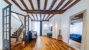 A spacious living area with wooden flooring, a staircase, a blue sofa, a guitar, and a mirror reflecting the room. - Triplex Belle Époque Hypercenter (Melun)