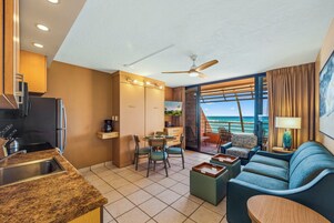 Habitación de hotel moderna con cocina, comedor y balcón con vista al océano.