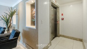 A modern lobby with a seating area, a reception desk, and an elevator. - Apartment With Balcony 500m From the Beach Emz0504 (Guarapari)