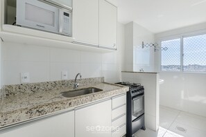 Una cocina moderna con armarios blancos, encimera de granito, microondas integrado y cocina a gas.