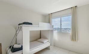 Camera con letto a castello, finestra con tende e vista sulla città.