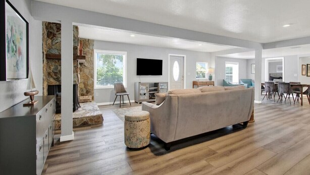Un amplio salón con un sofá grande, una mesa de comedor y un televisor montado en la pared.