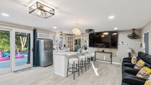 A modern kitchen with a central island, bar stools, and a dining area.